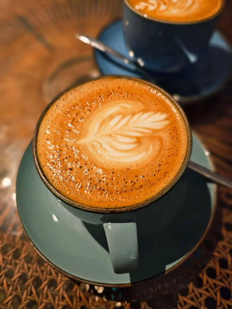Dwie filiżanki kawy z mlecznym latte art na drewnianym stoliku